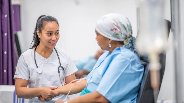 A healthcare worker tends to a patient receiving treatment in the hospital